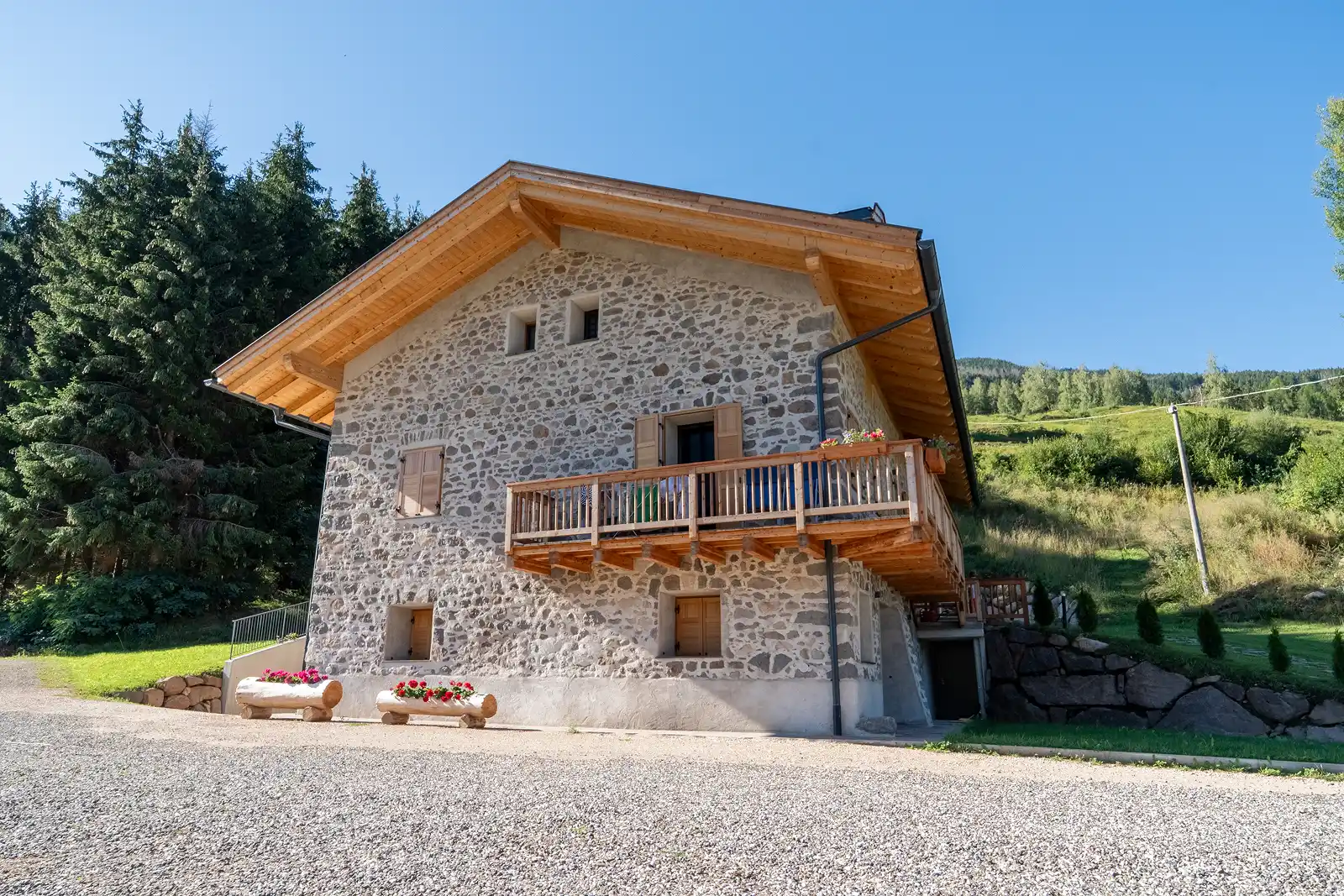 Chalet ristrutturato in pietre e legno, visto dalla strada a Lago di Tesero