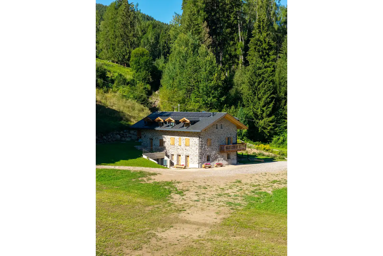 Chalet in pietra ristrutturata a Lago di Tesero con giardino e bosco sullo sfondo