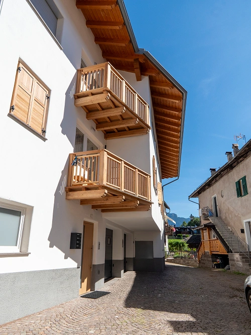 Vista scorcio di palazzina ristrutturata con sporgenza tetto in legno e poggioli artigianali, realizzazione 2R Group